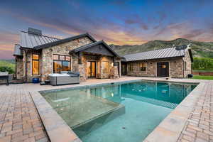 Outdoor pool with a hot tub, a patio area, and a mountain view