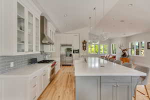 Kitchen featuring high quality appliances, a sink, gray cabinetry, a breakfast bar area, and vaulted ceiling