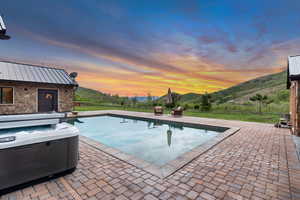Swimming pool with a patio, a mountain view, and a hot tub