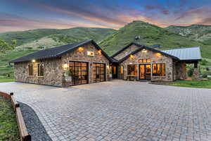 View of front of property with stone siding, a standing seam roof, a garage, metal roof, and a mountain view