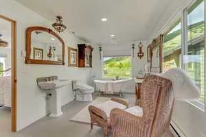 Bathroom with concrete floors, a soaking tub, baseboards, recessed lighting, and a baseboard heating unit