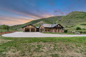 View of front of property featuring stone siding, curved driveway, a mountain view, a standing seam roof, and a chimney