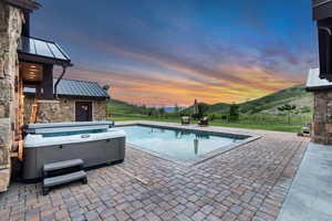 Swimming pool featuring a patio area, a mountain view, and a hot tub