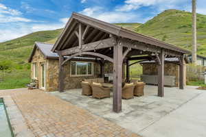 View of patio featuring a hot tub, a gazebo, an outdoor living space, and a mountain view