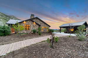 View of side of property with a chimney, stone siding, metal roof, and a standing seam roof