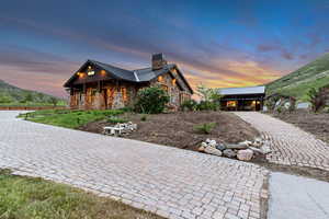 View of front of house with stone siding, a chimney, a standing seam roof, covered porch, and metal roof