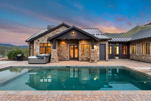 Rear view of house with a standing seam roof, a patio area, french doors, an outdoor pool, and metal roof