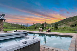 Swimming pool featuring a hot tub, a mountain view, a yard, and a patio area