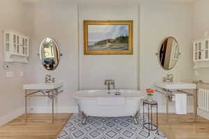 Bathroom featuring wood finished floors, radiator heating unit, a freestanding tub, and baseboards