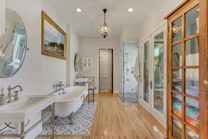 Full bath with a stall shower, a soaking tub, wood finished floors, a chandelier, and recessed lighting