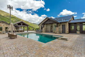 Outdoor pool with a gazebo, outdoor lounge area, a mountain view, a patio area, and a hot tub
