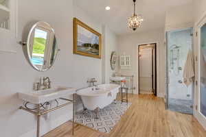 Bathroom with a stall shower, hardwood / wood-style flooring, a soaking tub, a chandelier, and recessed lighting