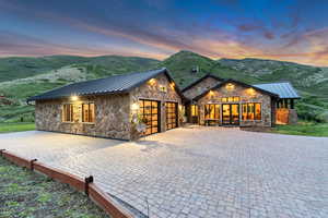 View of front facade featuring a standing seam roof, stone siding, an attached garage, metal roof, and a mountain view