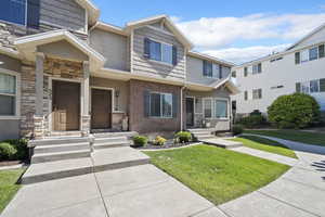 Multi unit property featuring a front yard and stone siding