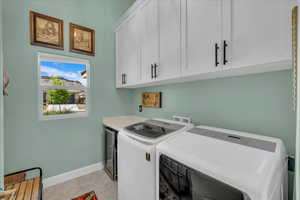 Laundry room with cabinet space, washer and clothes dryer, and light tile patterned flooring