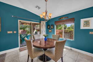 Dining space featuring vaulted ceiling, a chandelier, and light tile patterned floors