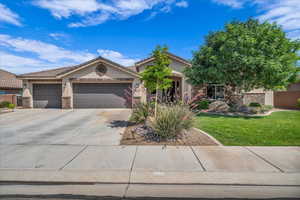 View of front facade featuring stucco siding, driveway, an attached garage, a front lawn, and stone siding