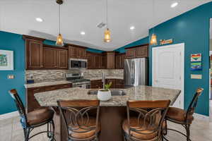 Kitchen with stainless steel appliances, tasteful backsplash, dark brown cabinets, a kitchen breakfast bar, and vaulted ceiling