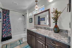 Bathroom featuring vanity, shower / tub combo with curtain, and tile patterned flooring