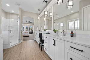 Bathroom with a ceiling fan, a shower stall, vanity, wood finished floors, and recessed lighting