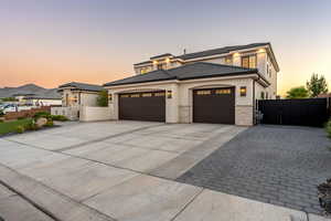 Prairie-style house with driveway, an attached garage, a gate, and stucco siding