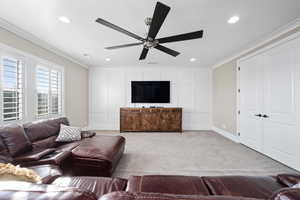 Living area featuring crown molding, a decorative wall, light colored carpet, ceiling fan, and recessed lighting