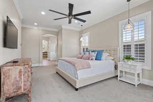 Carpeted bedroom with arched walkways, crown molding, recessed lighting, and ceiling fan