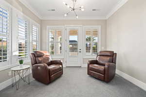 Sitting room featuring a chandelier, crown molding, and carpet flooring