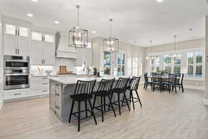 Kitchen featuring premium range hood, stainless steel double oven, a chandelier, light countertops, and recessed lighting