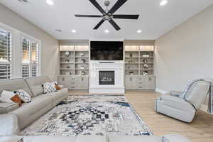 Living area featuring a ceiling fan, a glass covered fireplace, recessed lighting, and light wood-type flooring