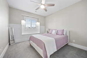 Carpeted bedroom with a ceiling fan and baseboards