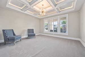 Living area with a chandelier, coffered ceiling, carpet floors, and beam ceiling