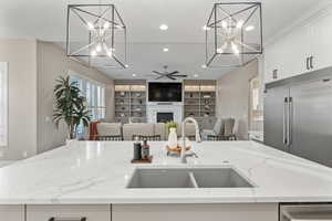 Kitchen with appliances with stainless steel finishes, open floor plan, light stone countertops, recessed lighting, and white cabinets