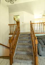 Staircase featuring a ceiling fan and tile patterned floors