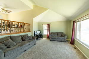 Living area with ceiling fan, vaulted ceiling, and carpet floors