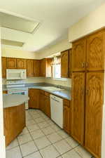Kitchen featuring white appliances, brown cabinets, light countertops, and light tile patterned floors