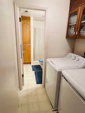 Laundry room with washing machine and clothes dryer, light flooring, and cabinet space