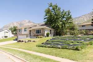 Tri-level home with stone siding, a mountain view, driveway, and an attached garage