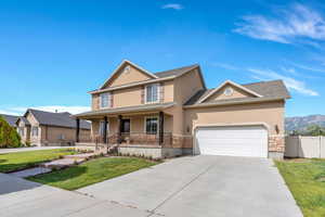 View of front of property with a porch, stucco siding, stone siding, concrete driveway, and a garage