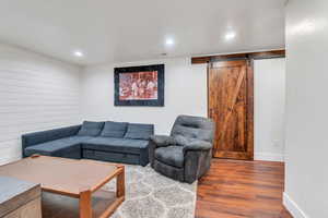 Living area with wood finished floors, a barn door, and recessed lighting
