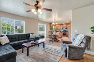 Living area with light wood-type flooring, a ceiling fan, a chandelier, a textured ceiling, and recessed lighting