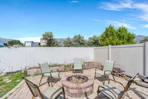 Fenced backyard featuring an outdoor fire pit, a patio, and a mountain view
