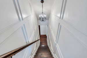 Stairway with a chandelier, wood-type flooring, and a decorative wall