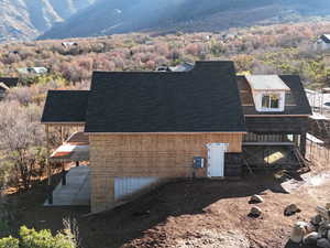 View of side of home featuring a shingled roof and a mountain view