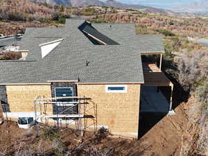 View of side of property with a shingled roof and a deck with mountain view