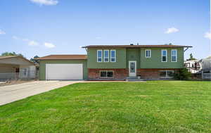 Bi-level home with a garage, concrete driveway, and brick siding