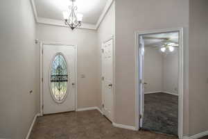 Entrance foyer featuring a ceiling fan, a chandelier, and baseboards