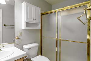 Bathroom with vanity, a shower with shower door, and toilet