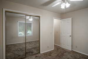 Unfurnished bedroom featuring carpet floors, a closet, ceiling fan, baseboards, and a textured ceiling