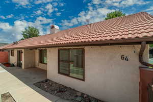 Back of property with stucco siding, a tile roof, a patio area, and a chimney